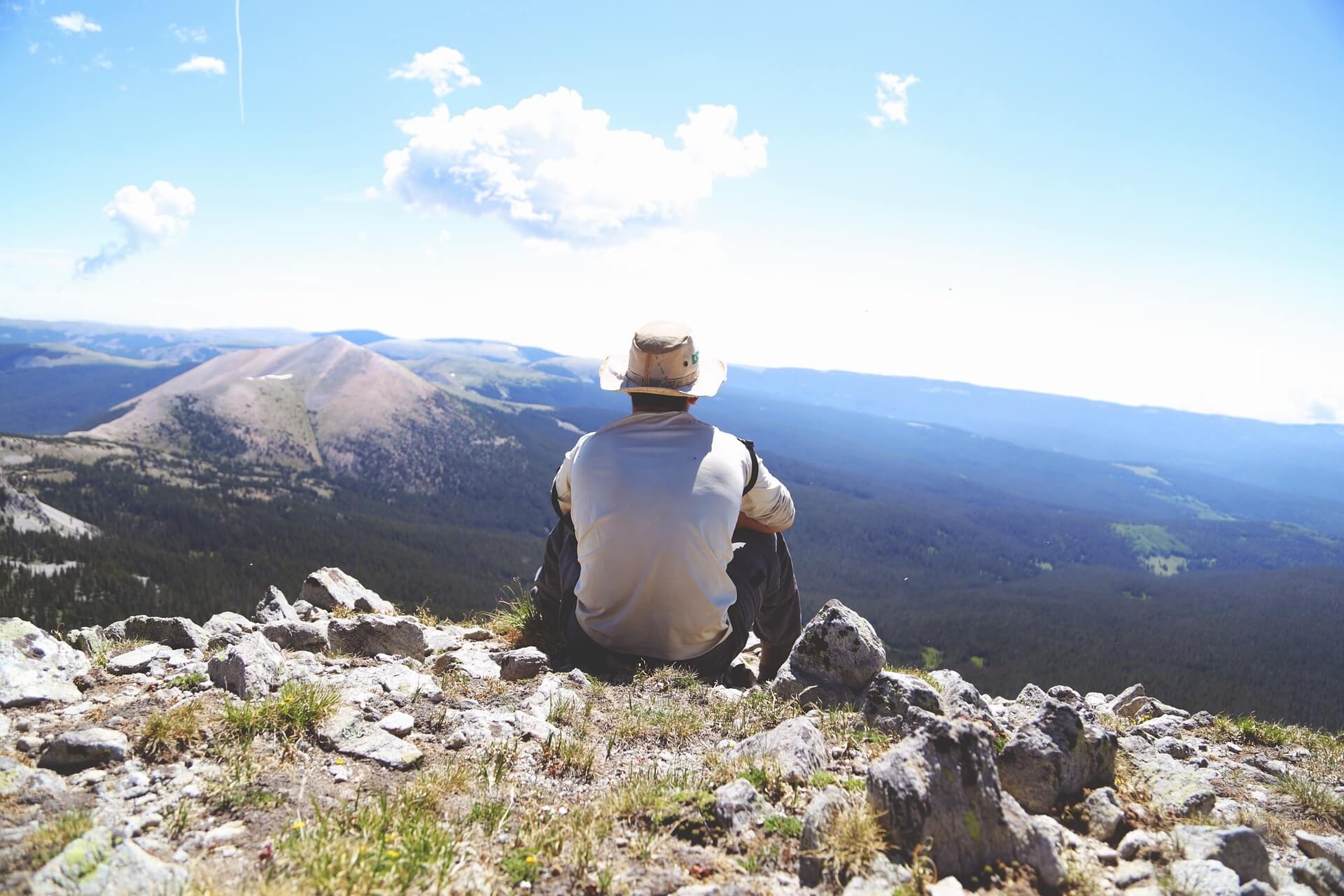 man staring at the horizon on top of a mountain