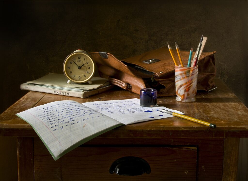 desk with papers, a clock and pens.